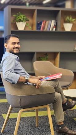 Ashham Saleel in a chair, looking at the camera and smiling.