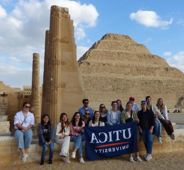 Students hold up a Utica University banner at Saqqara during a January 2023 trip to Egypt.